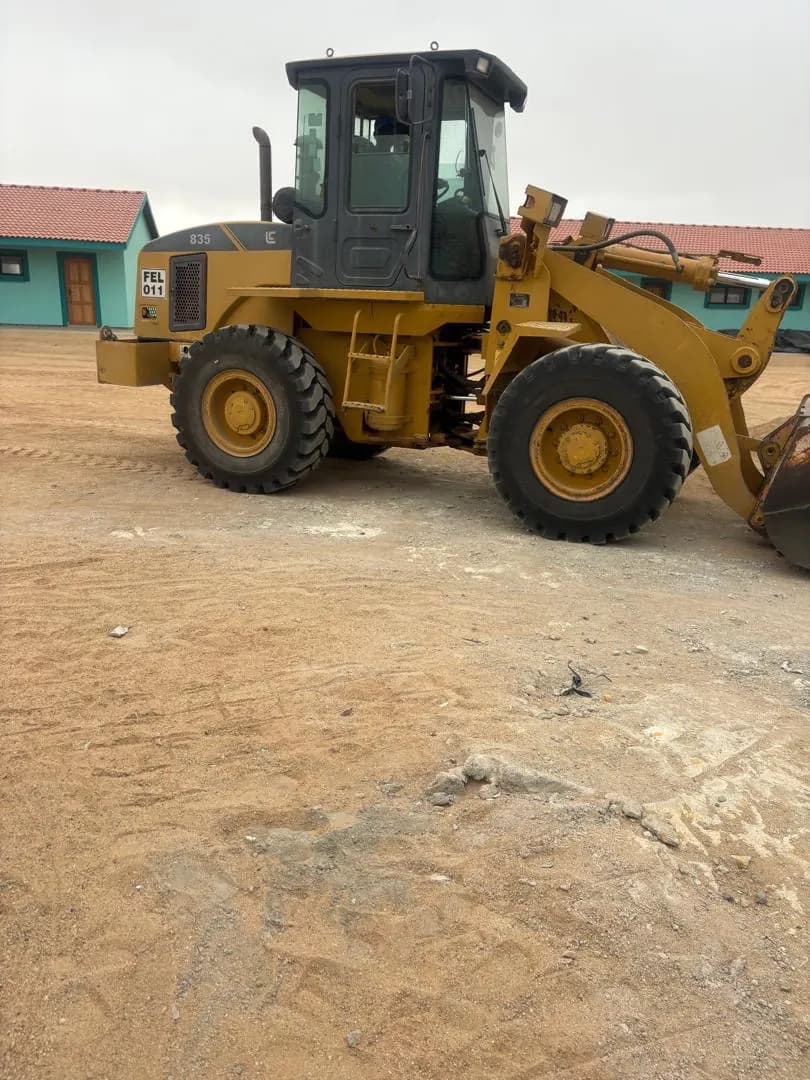 Front-end loader shaping and levelling ground in front of new classroom blocks at the Henties Bay school site