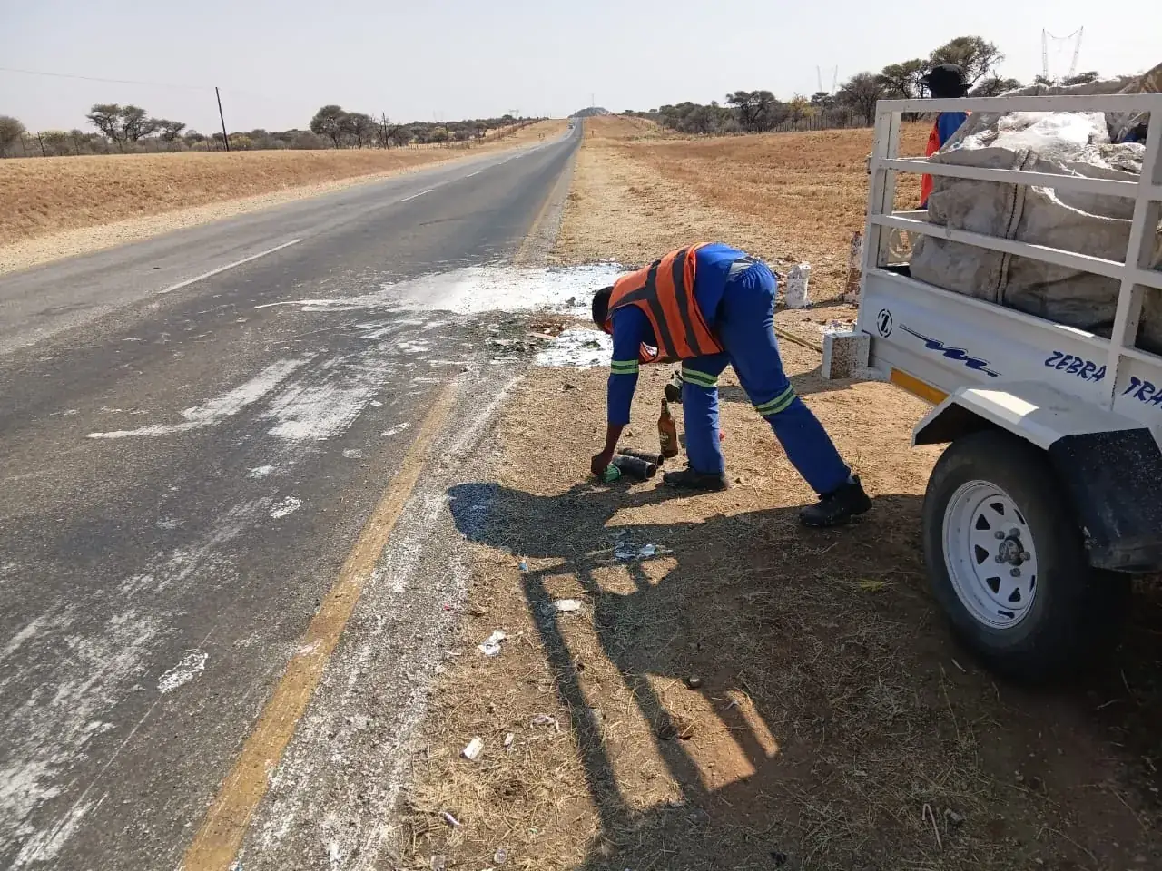 Road worker patching a surface beside a trailer