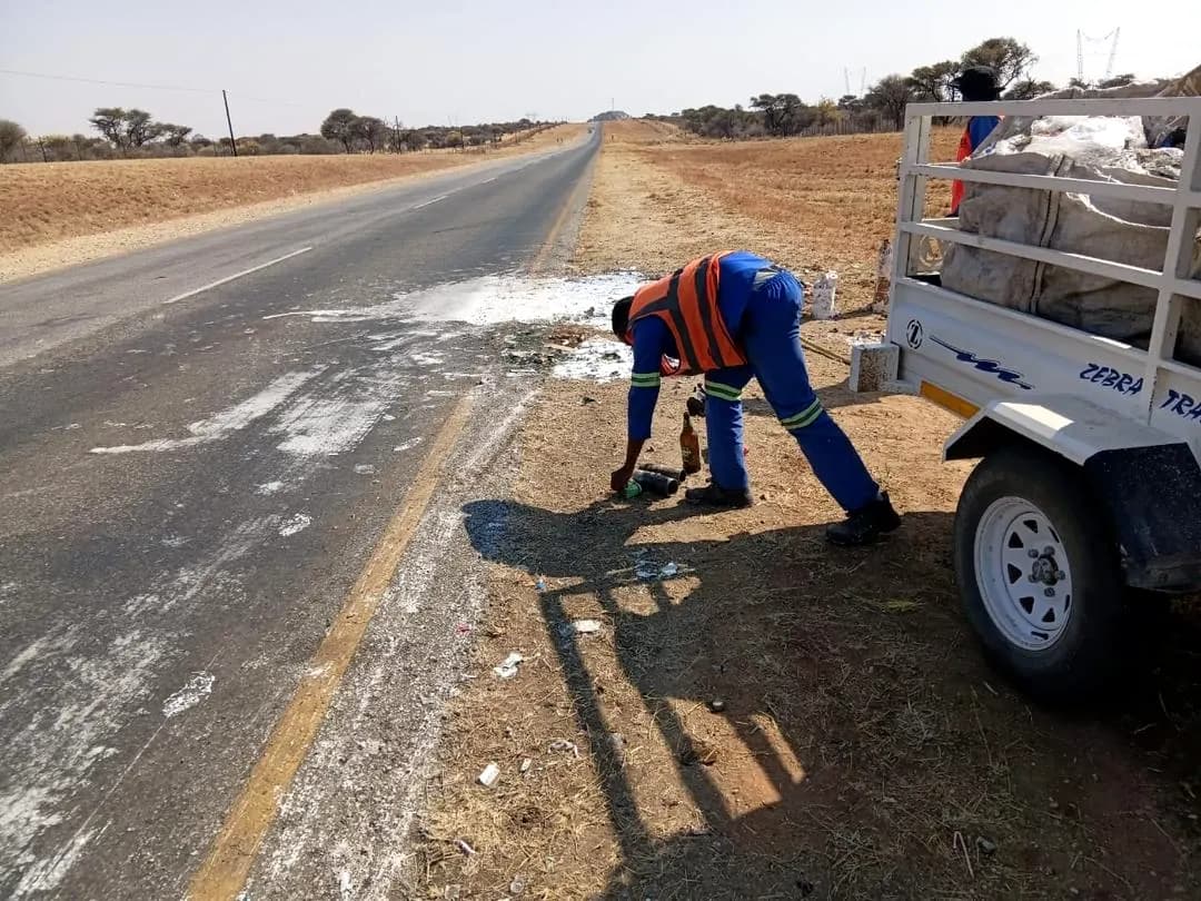 Worker in high-visibility clothing offloading fencing materials from a trailer