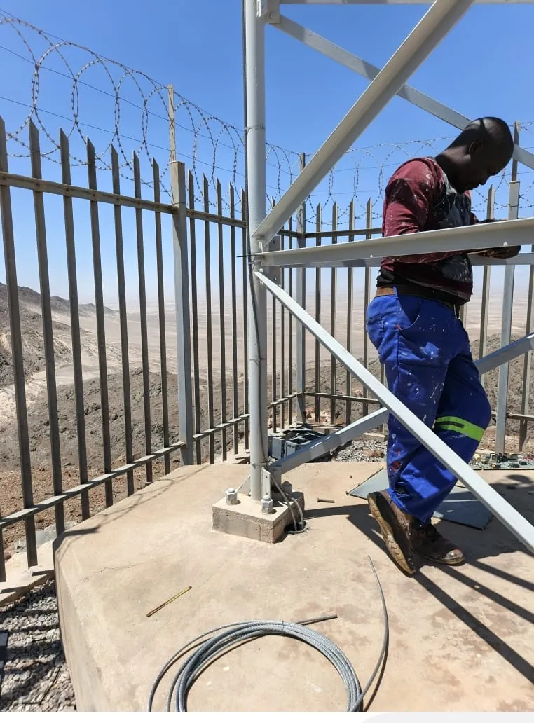 Technician working at a tower base behind a security fence