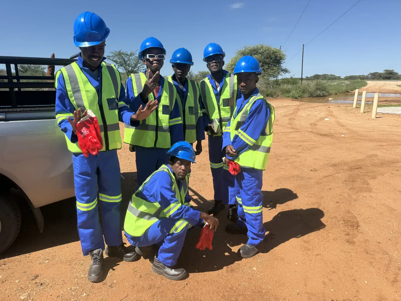 Mendozer crew in blue helmets and branded high-visibility wear beside a site vehicle